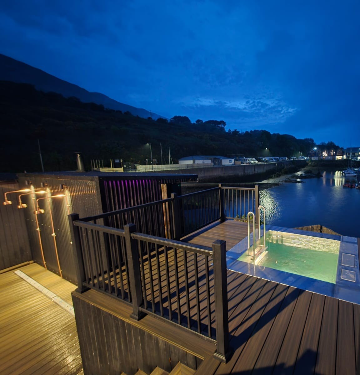 Composite deck at dusk overlooking Carlingford Marina, with lit plunge pools and outdoor showers