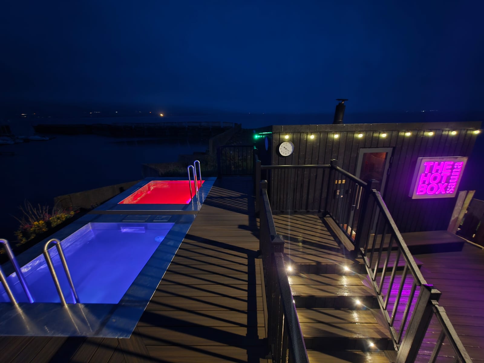 Composite deck with lit plunge pools overlooking the marina at dusk